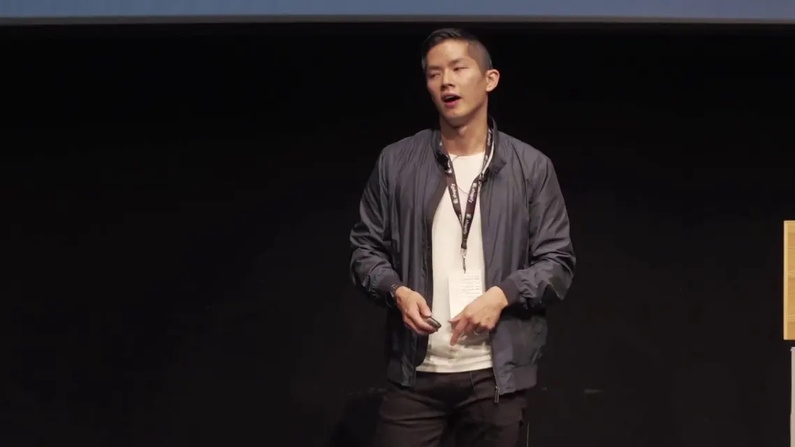 Brandon on stage in a dark jacket and a white T-shirt