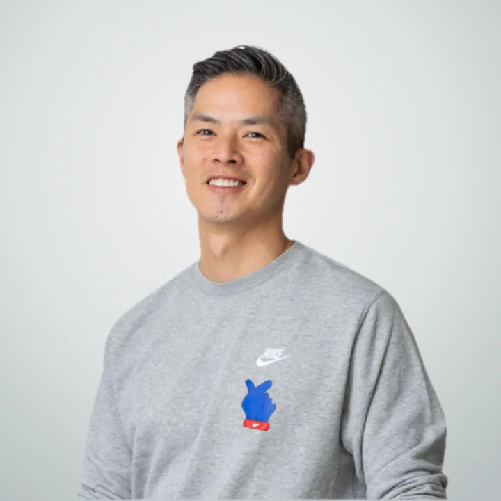Brandon smiling, in a grey sweatshirt, against a light grey wall